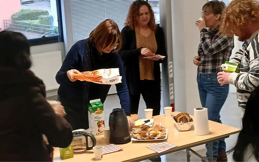 Une chargée de mission sert le café et les croissants à des bénéficiaires.