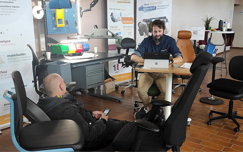 Stand d'un partenaire avec une personne essayant un fauteuil ergonomique.
